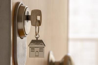 Close up of key and house keychain ​​in high security door lock. Home insurance concept.