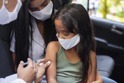 Small girl receiving vaccination with mother in car