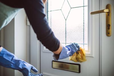 Woman in household cleaning gloves cleaning the door with cloth