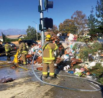 A Chino Valley Fire District firefighter sprays water on trash