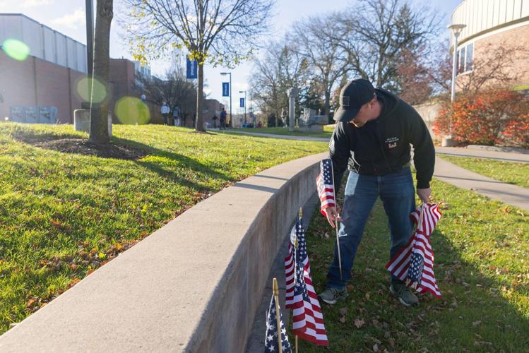 A student places flags in the MSC Amphitheatre for Veteran's Day.