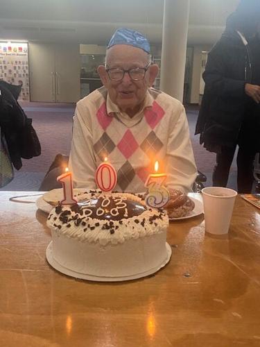 Dr. Malcolm Brahms prepares to blow out the candles on his 103rd birthday cake