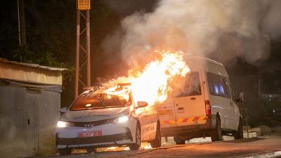 An Israel Police patrol car burns in Lod