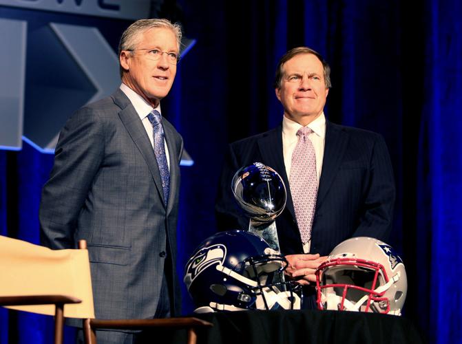 Seattle Seahawks head coach Pete Carroll and New England Patriots head coach Bill Belichick pose for a photo behind their helmets and the Vince Lombardi Trophy before their joint press conference in Phoenix.