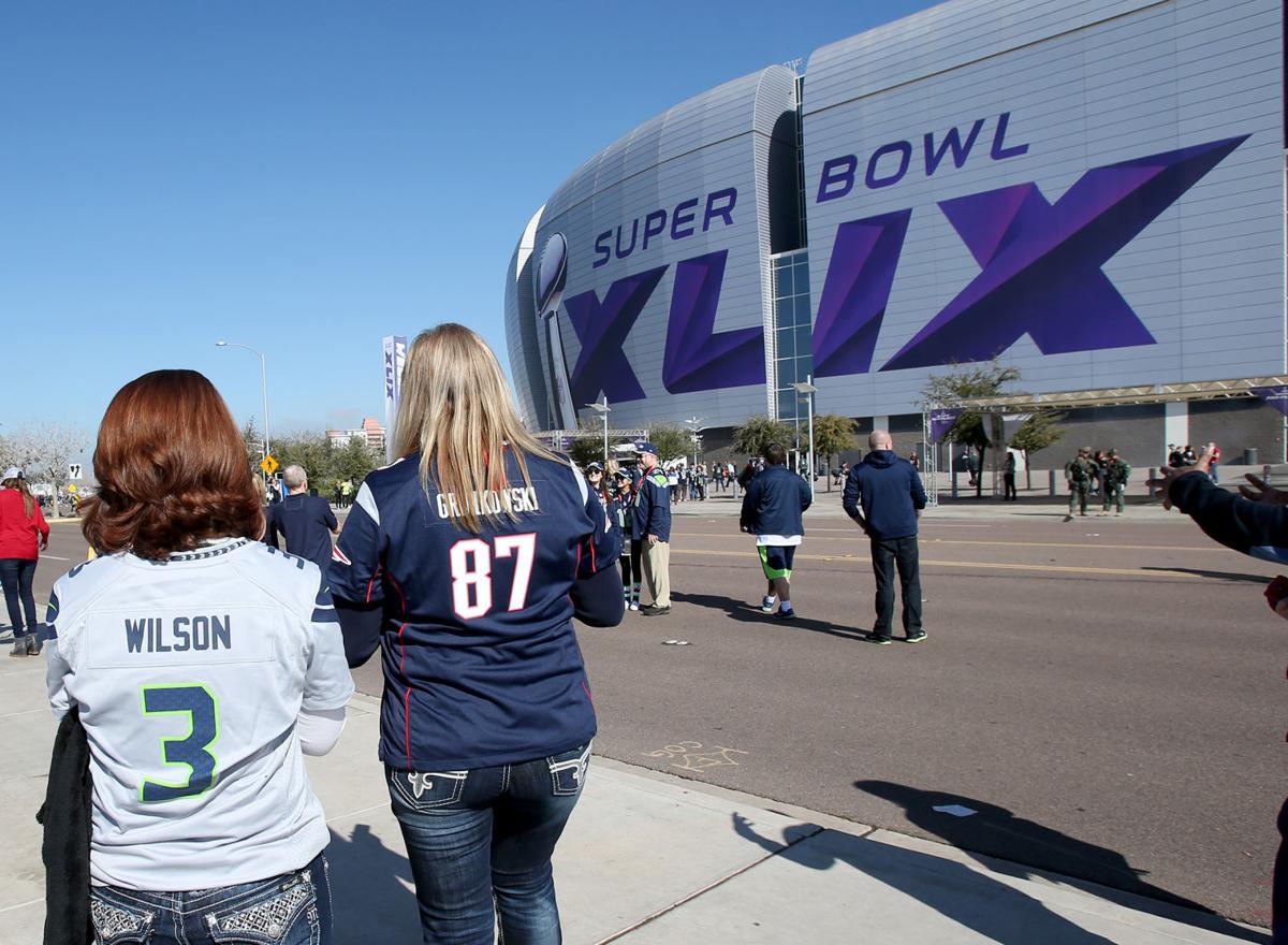 Friends and dueling fans walk to the stadium entrance before the start of Super Bowl XLIX in Glendale, Ariz.