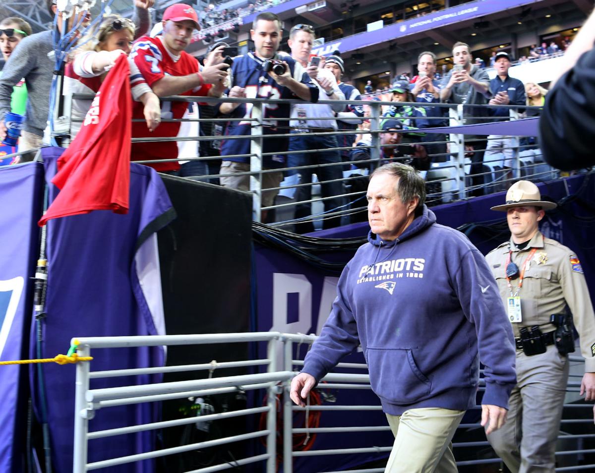 New England Patriots head coach Bill Belichick walks on to the field as fans try to get a photo before the start of Super Bowl XLIX .