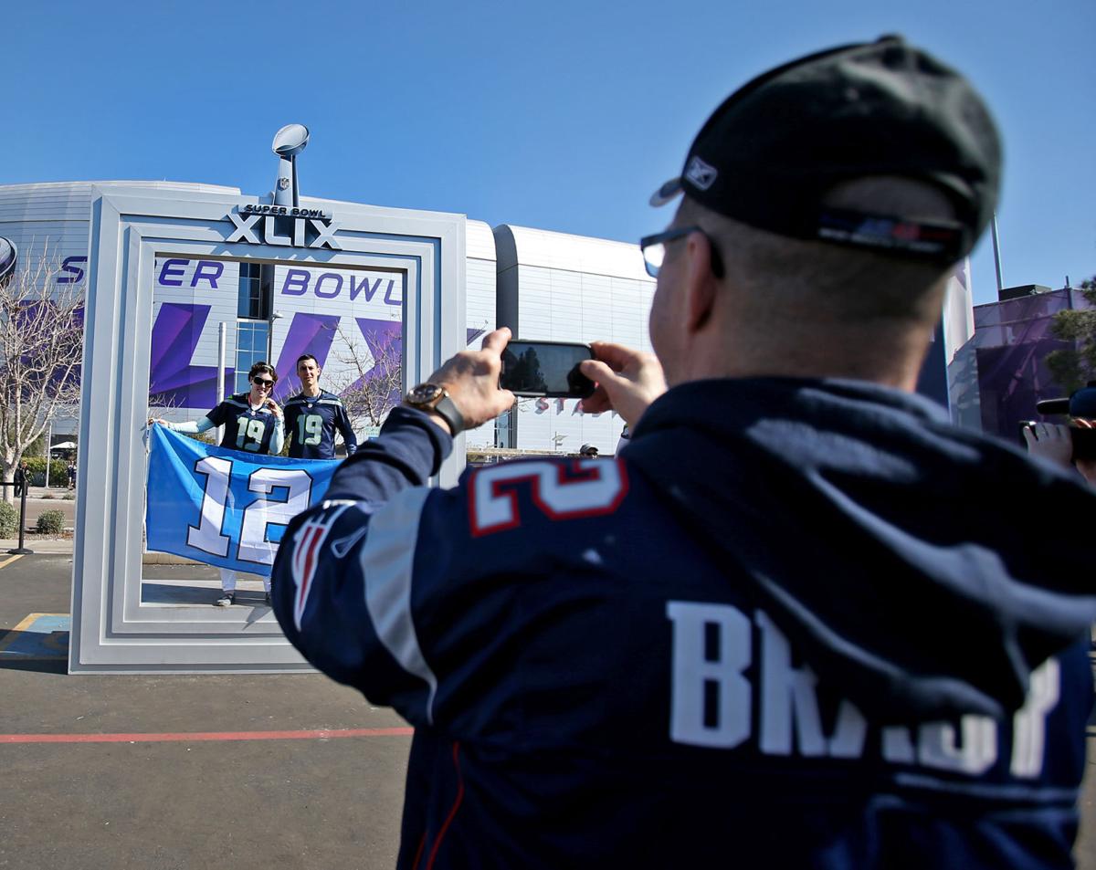 A New England Patriots fan takes photos of his Seattle Seahawks friends