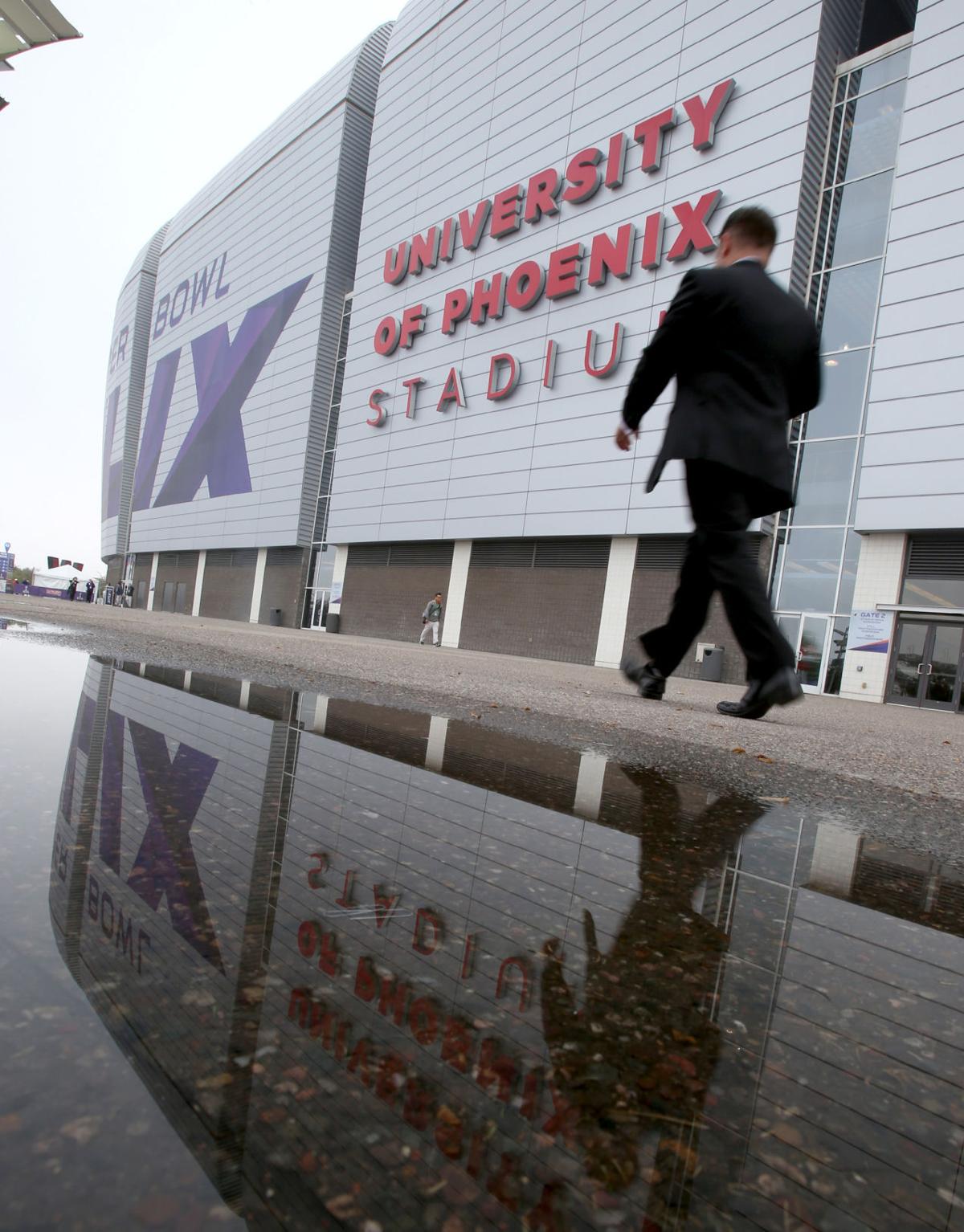 The University of Phoenix Stadium is reflected in a puddle well before the start of Super Bowl XLIX in Glendale, Ariz.