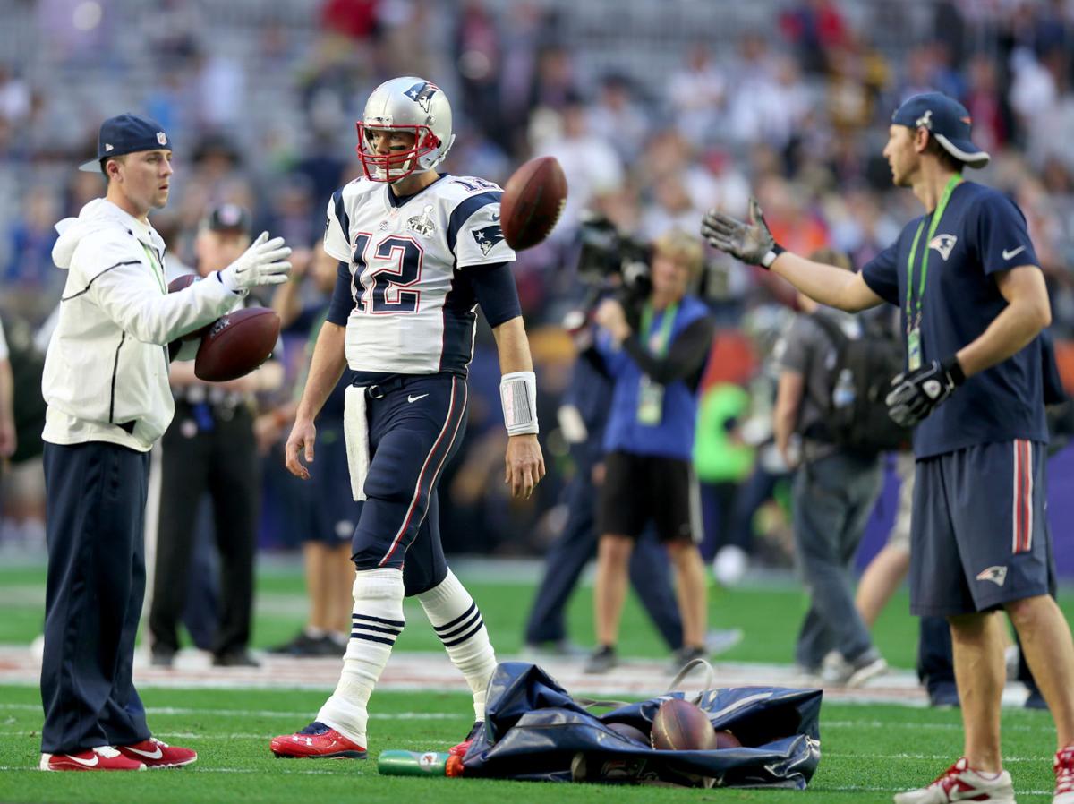 Patriots staff toss balls from a bag as New England Patriots quarterback Tom Brady peppers to take warmup throws.