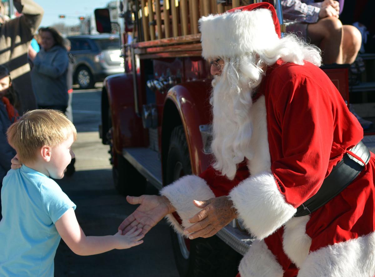 Nolan Hauder 4 greets Santa with a low five Saturday in downtown Columbus Santa arrived on a vintage firetruck and spent the afternoon inside his house