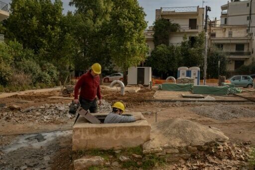 Christos Geovanopoulos (L) and Yannis Dafnos enter a settling basin in Chalandri