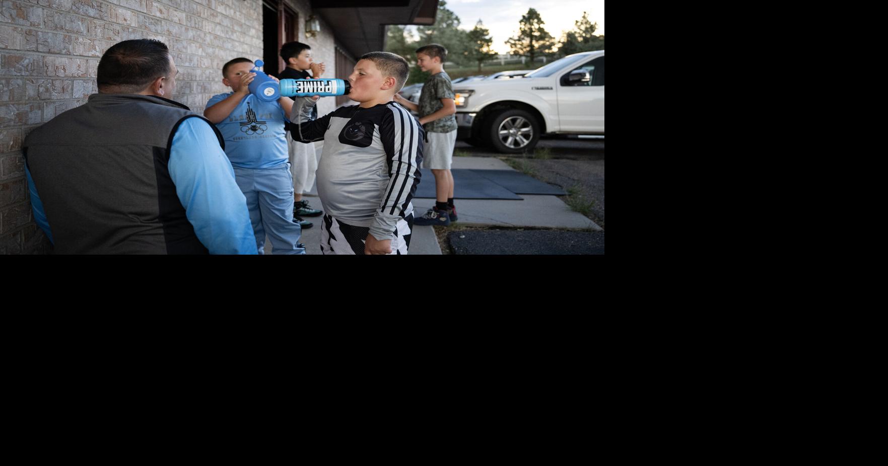 Wrestlers Vinny Amorosa, 10, right, and his younger brother Gino Amoroso, 8, take a water break while talking to their father Joe Amorosa during a practice at Black Fox Wrestling Academy on Wednesday, Aug. 19, 2026, in Franktown, Colo..