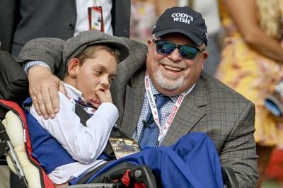 Cody Dorman, beside his father Kelly, as they watch Cody’s Wish in the paddock