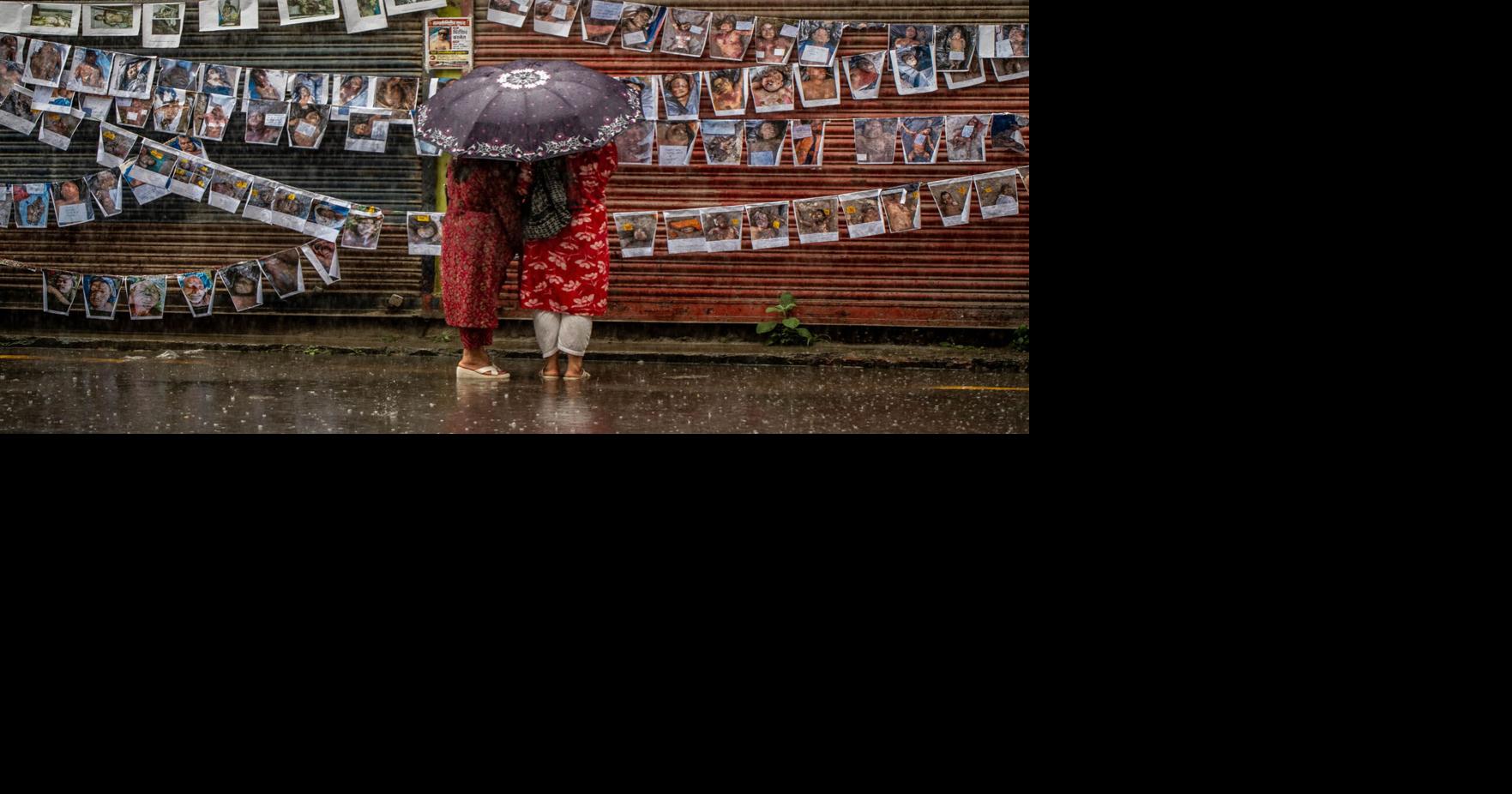 Relatives stand in the rain near a wall covered with posters of missing people outside the Tribhuvan University Teaching Hospital in Kathmandu, Nepal.