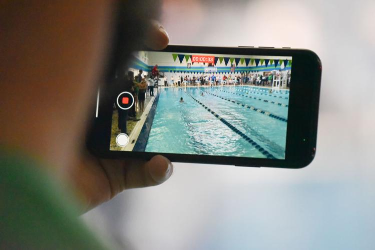 A coach films a heat during the meet on Friday.