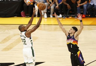 The Milwaukee Bucks' Khris Middleton puts up a shot against the Phoenix Suns' Devin Booker during the first half in Game 1 of the NBA Finals at Phoenix Suns Arena on July 6, 2021 in Phoenix.