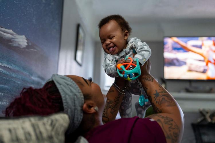 Rakiah Reives, 33, a medical assistant, plays with Jakai Reives, 5 months, inside her home in Detroit on Tuesday, May 5, 2026. Reives is one of several mothers receiving cash payments through the Rx Kids program, which aims to ease the financial strain of