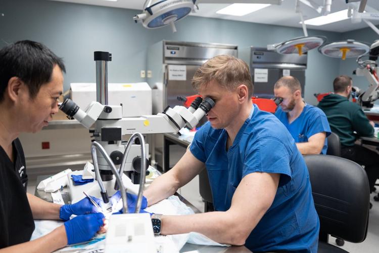 On left, Weifeng Zeng, senior scientist of UW Microsurgery, practices repairing blood vessels in a chicken thigh with Ukrainian surgeons at the UW Microsurgery Regenerative Medicine Lab in Madison in April. The plastic surgery division hosted six Ukrainian