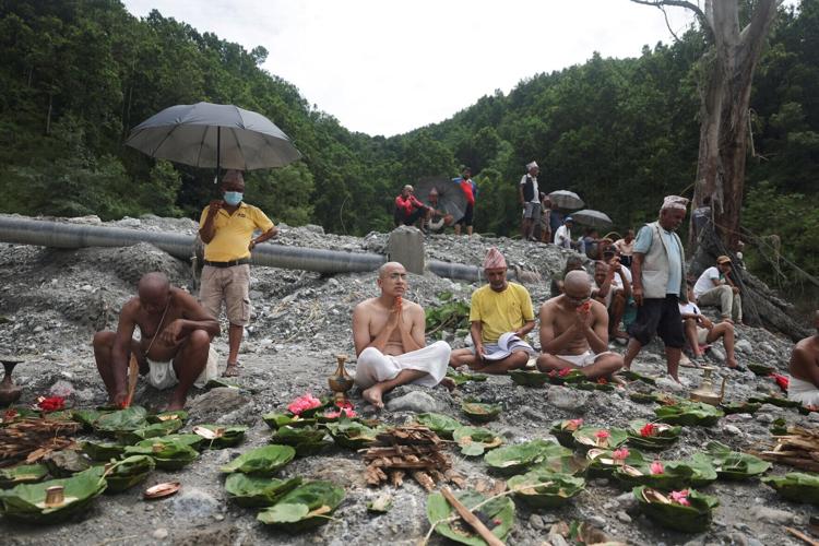 Men perform last rites for missing family members after being unable to recover their bodies following flash floods and mudslides, in Trishuli