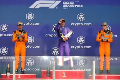Mercedes driver Kimi Antonelli (center), and McLaren drivers Lando Norris (left) and Oscar Piastri (right) react on the stage after the Crypto.com Miami Grand Prix at Miami International Autodrome on May 3, 2026.