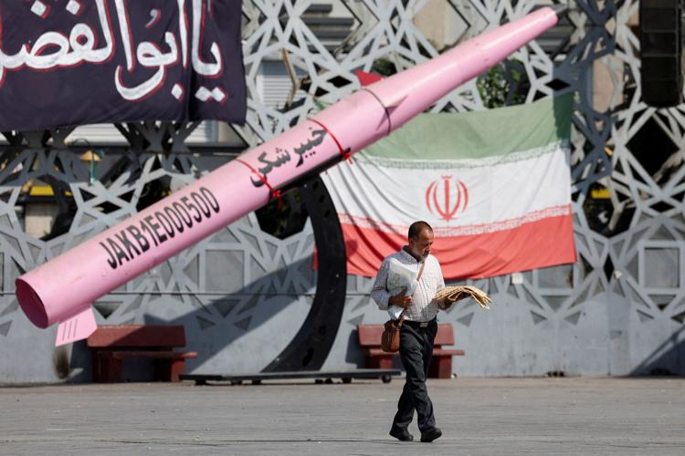 FILE PHOTO: A man walks next to a symbolic mockup of an Iranian missile at Imam Hussein Square in Tehran