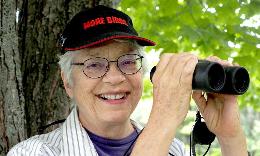 Margaret Carney smiling and holding up binoculars