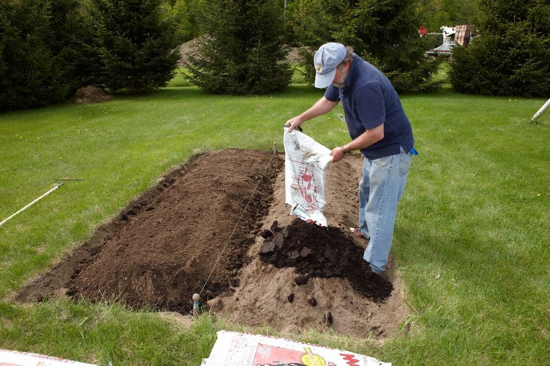Image of Person raking compost into the soil of a lawn