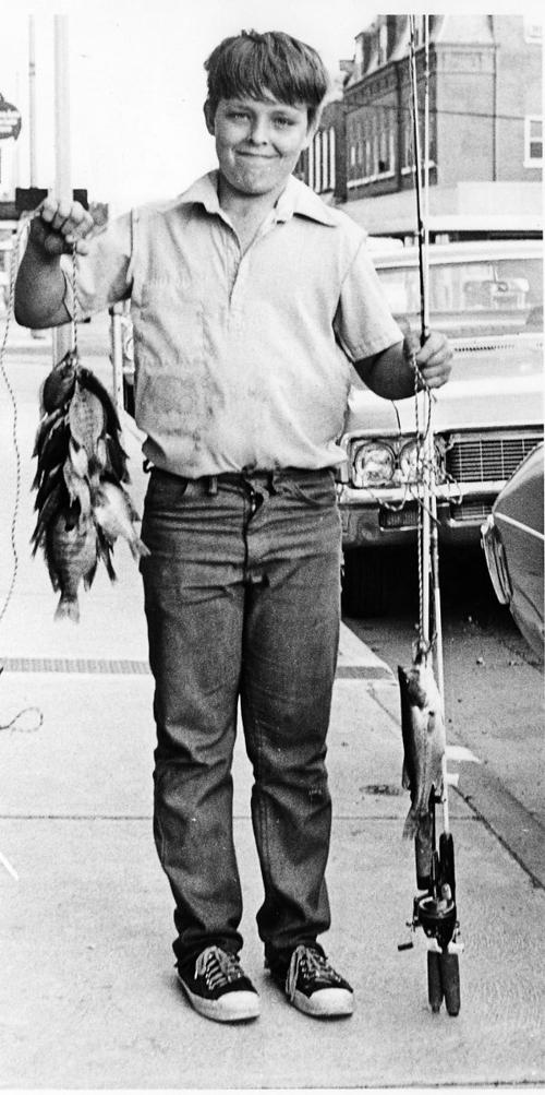 Boy holds many fish on main street