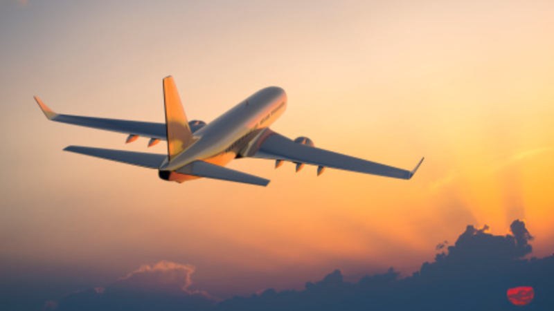 Passenger airplane flying above clouds during sunset.