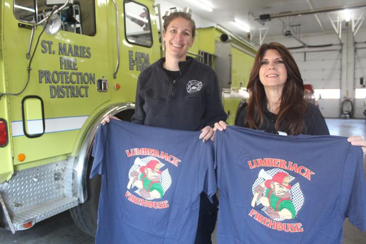 The St. Maries Fire Protection District is selling t-shirts to support its benevolence fund. Pictured: Captain Marcella Reed (left), and administrative assistant Cary Rubiera (right).