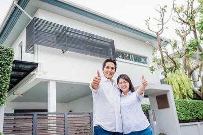 Asian couple standing together in front of thier house