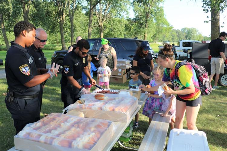 Forest City Police Officers and Police Chief Tom Montgomery greet Adley, Haizlee, and Tiffany Ahrens with hot dogs provided by Hy-Vee..JPG