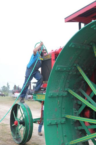 Tyler Kester of Illinois takes a water hose to The Flour City antique prairie tractor of Kinnard & Sons Manufacturing of Minneapolis..JPG