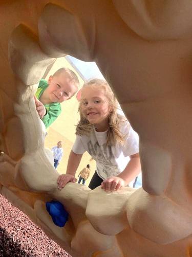 Two West Hancock Elementary School students peer through an opening on a new climbing tunnel in Britt..jpg