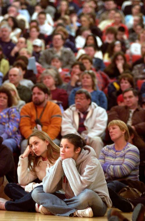 Fourteen-year-olds Rachel Federico, left, and Laura Clark, found a spot to sit on the floor in the packed auditorium of Salem High School at a forum on drug addiction.