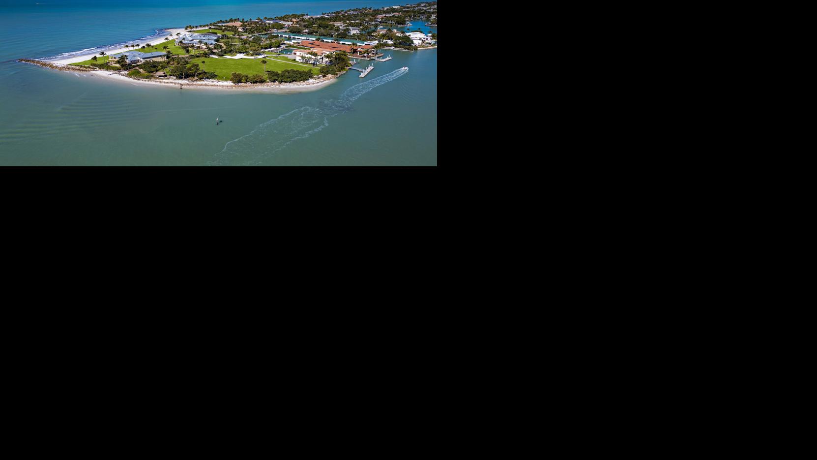 An aerial view shows Gordon Pointe, a nearly 9-acre private peninsula estate at 100 Bay Road in Naples, with frontage on both the Gulf of Mexico and Naples Bay. The legacy compound has returned to the market after a previous record-setting listing in 2024.