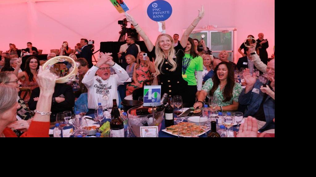 Guests celebrate during the live auction at the Naples Winter Wine Festival, where a luxury “Paying It Forward” lot will be offered Jan. 31, 2026, featuring a VIP experience at the 2027 festival, a custom Mercedes luxury limo sprinter van and a $30,000 fine jewelry credit.