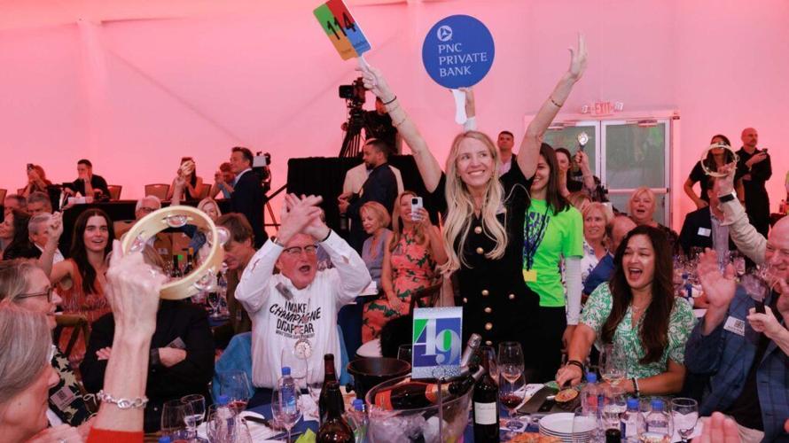 Guests celebrate during the live auction at the Naples Winter Wine Festival, where a luxury “Paying It Forward” lot will be offered Jan. 31, 2026, featuring a VIP experience at the 2027 festival, a custom Mercedes luxury limo sprinter van and a $30,000 fine jewelry credit.