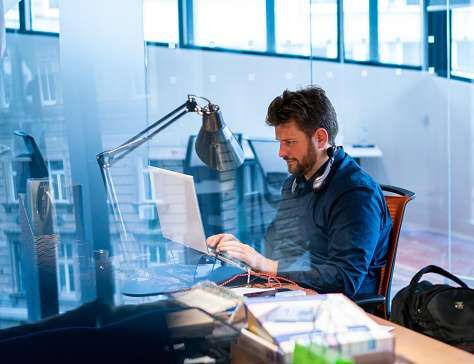 Focused male computer programmer working on laptop at desk in office