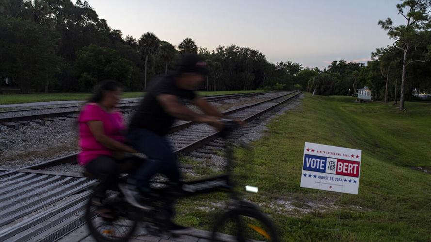 Cyclists pass BERT campaign sign in Bonita Springs