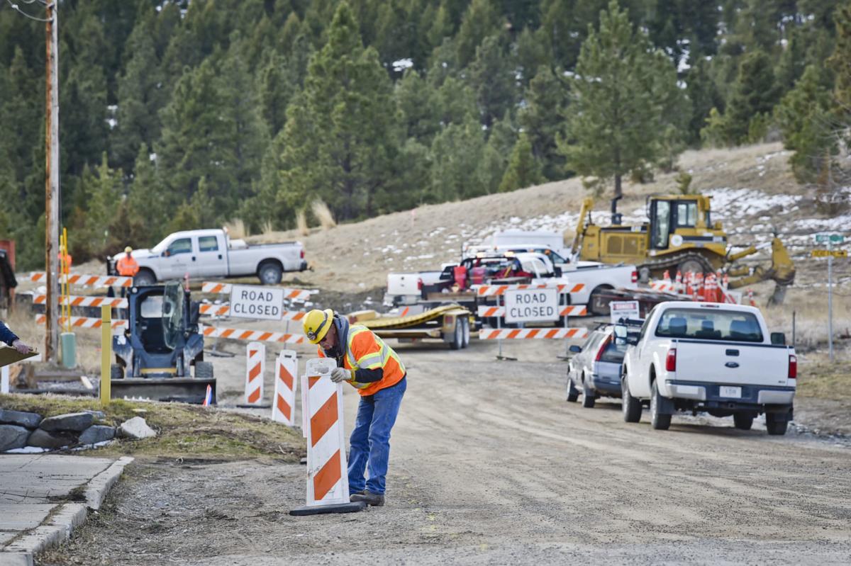 A construction worker hangs signage Monday as construction started on the new Beattie Street Trailhead.