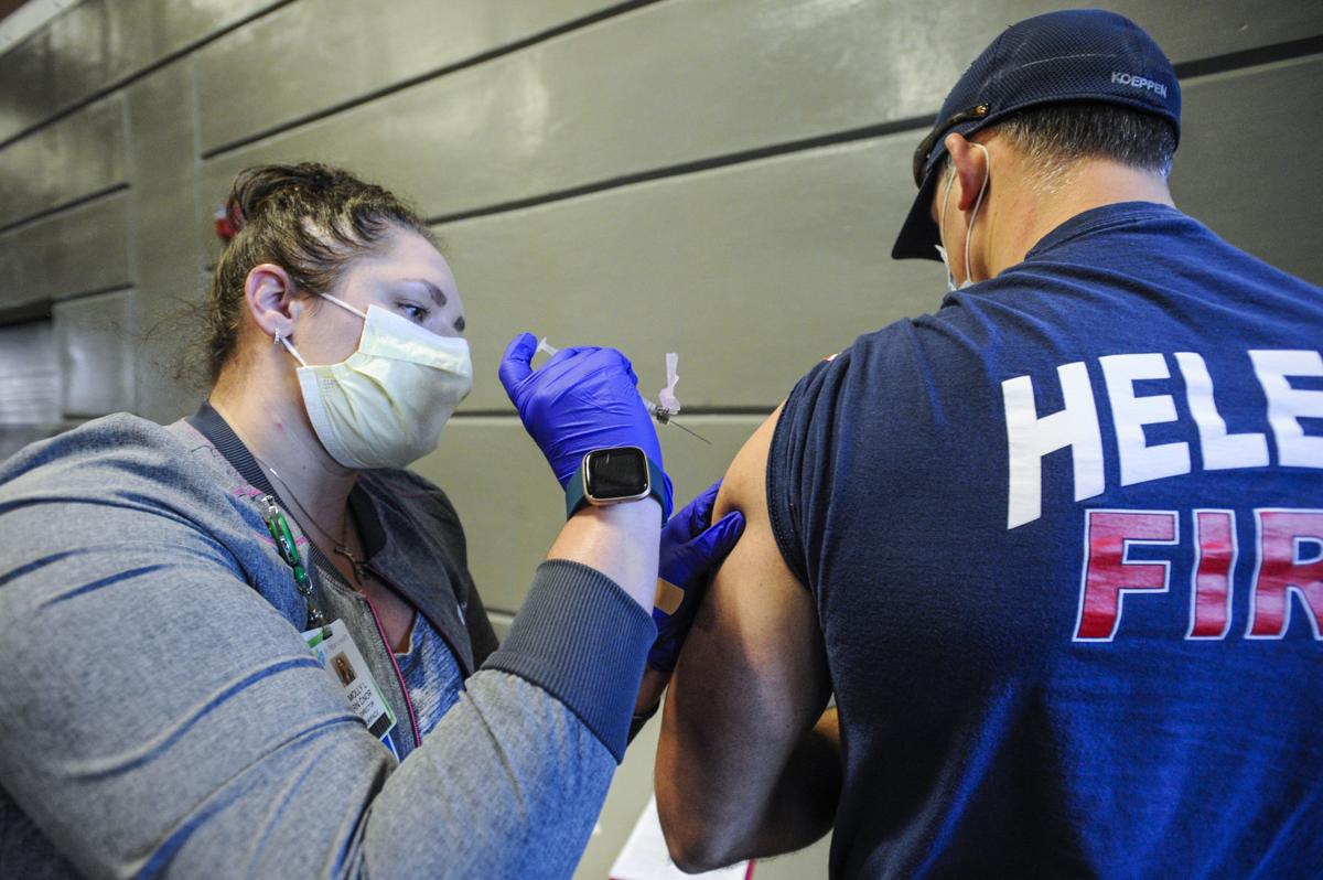 Molly Litchfield, left, vaccinates Helena firefighter Owen Koeppen