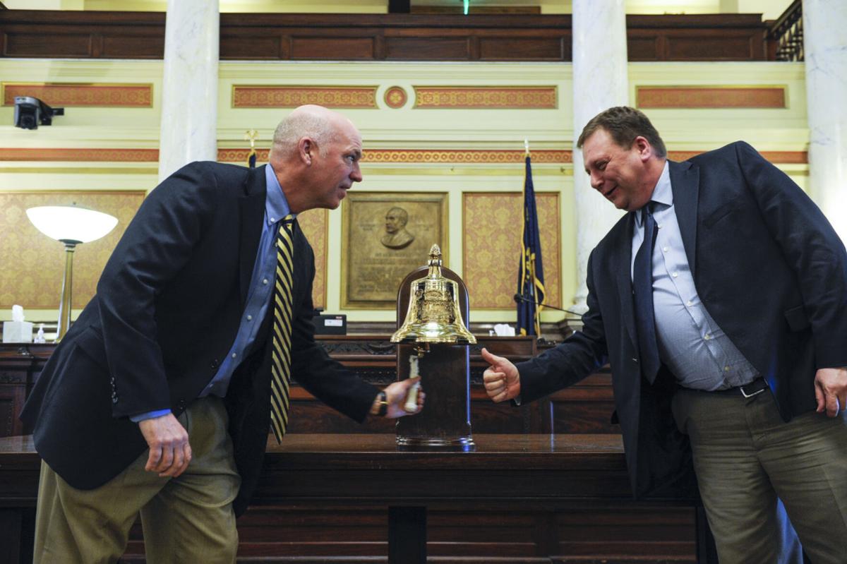 Gov. Greg Gianforte, left, and Senate President Sen. Mark Basdel, ring the replica USS Montana
