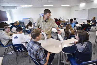 Science teacher Thomas Shive hands out materials to his ninth grade students