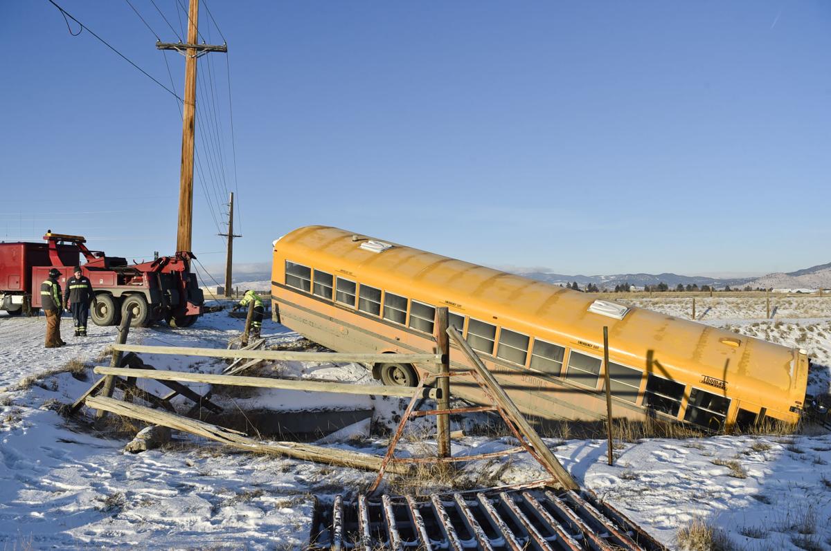 A wrecking crew works to pull a school bus out of the irrigation ditch