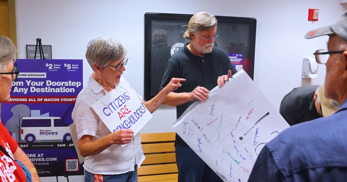 Illinois People's Action delivers banner to Macon County Board offices