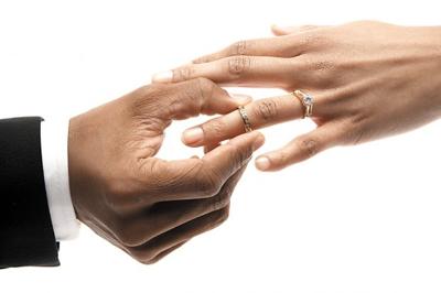 Man placing wedding ring on woman's finger, close-up