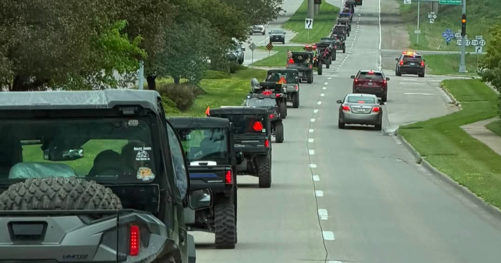 Side-by-side riders wave to hospitalized children from Kinnick