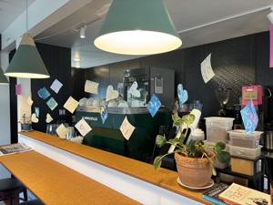 Other Text Notes of encouragement from Bonners Ferry, Idaho, hang above the espresso machine at Heights Coffee Bar in Columbia Heights, part of a 1,000-card effort organized in solidarity after ICE activity in Minnesota. Top left inset: Cards are hung at Heights… Alt Text