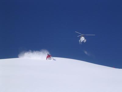 A skier going down a slope after being dropped by a helicopter